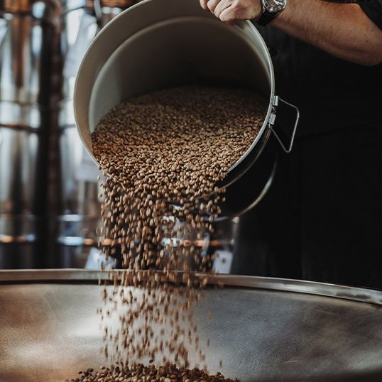 Kaffeebohnen werden in den Röster geschüttet